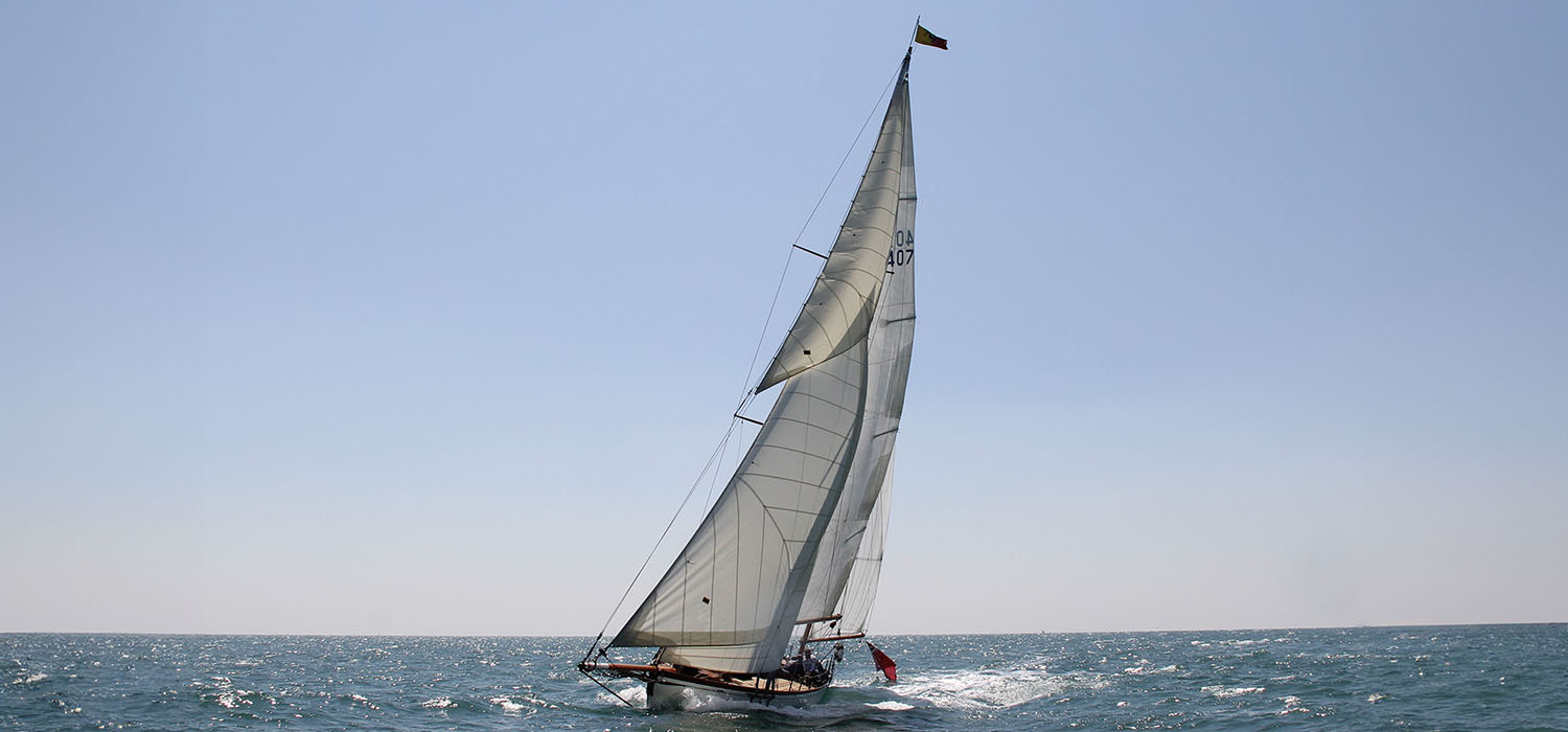 Beautiful wooden cruising yacht, sailing in the sunshine, flying Dart sails