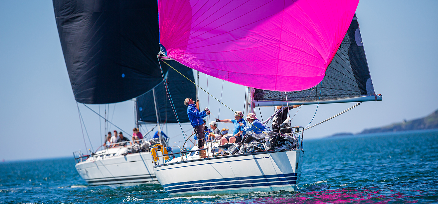 Racing yachts, first boat is flying Dart Sails, including a pink spinnaker