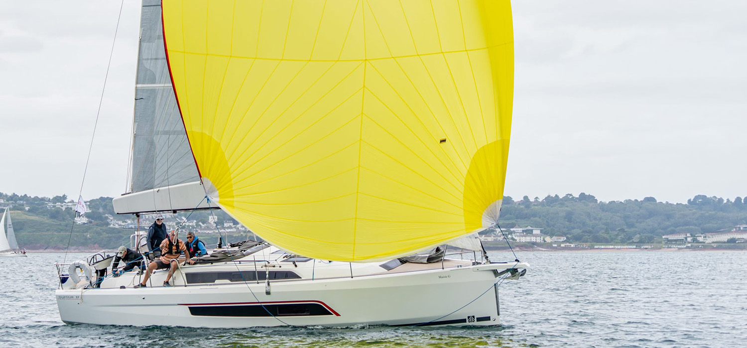 Dufour 37 sailing downwind with yellow spinnaker Dufour 37 sailing and racing downwind, flying a bright yellow spinnaker, designed and made by Dart Sails